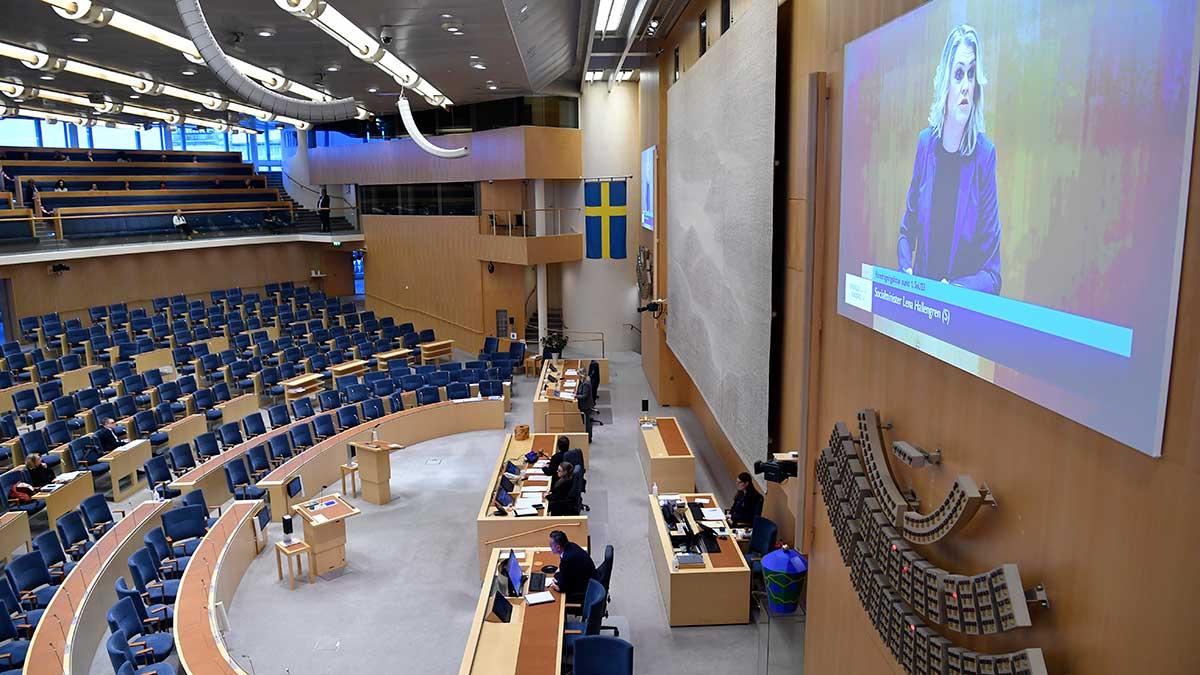 En extrainkallad riksdag klubbade i dag den nya och tillfälliga pandemilagen. På stora bildskärmen syns socialminister Lena Hallengren (S). (Foto: TT)