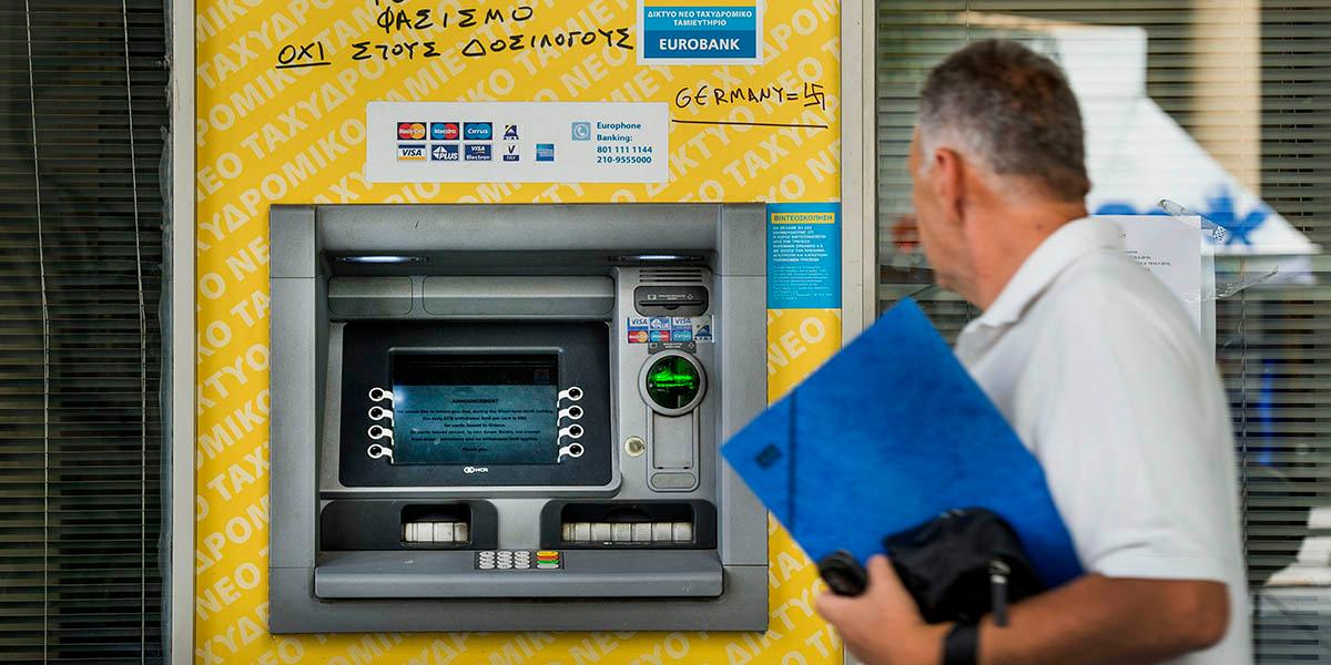 En man framför en bankomat i Grekland.