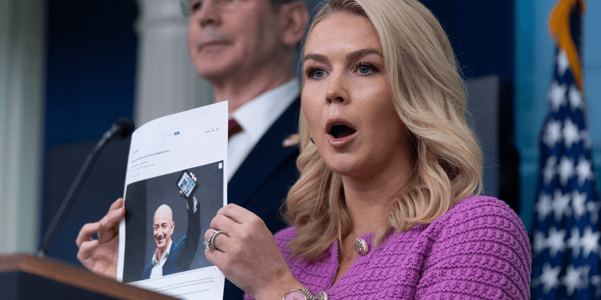 Vita husets pressekreterare Karoline Leavitt, med finansminister Scott Bessent, till vänster i bakgrunden, visar en bild av Jeff Bezos när hon svarar på en fråga om Amazon, under en presskonferens i James Brady Press Briefing Room i Vita huset. (Foto: Manuel Balce Ceneta/AP/TT)
