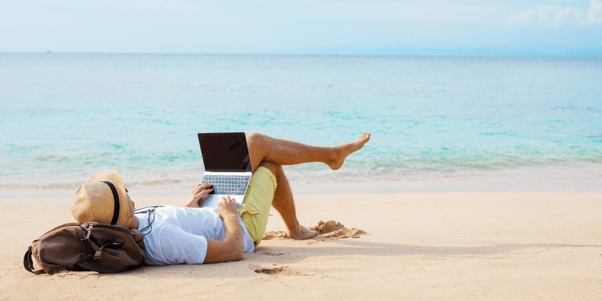 Man på strand med laptop symboliserar passiv inkomst och ekonomisk frihet.