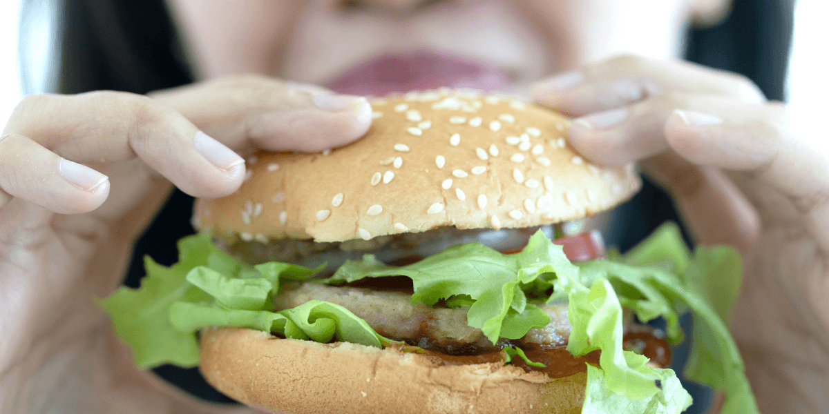 kvinna äter snabbmat.