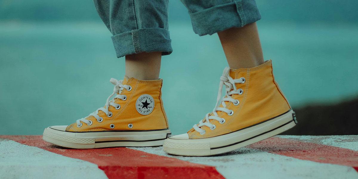 Basketskorna från Converse känns igen av de flesta. Men företaget har varit dåligt på att följa ungdomstrender, vilket resulterat i en sjunkande försäljning. (Foto: Unsplash) Närbild på fötter iklädda gula basketskor från Converse. (Foto: Unsplash)