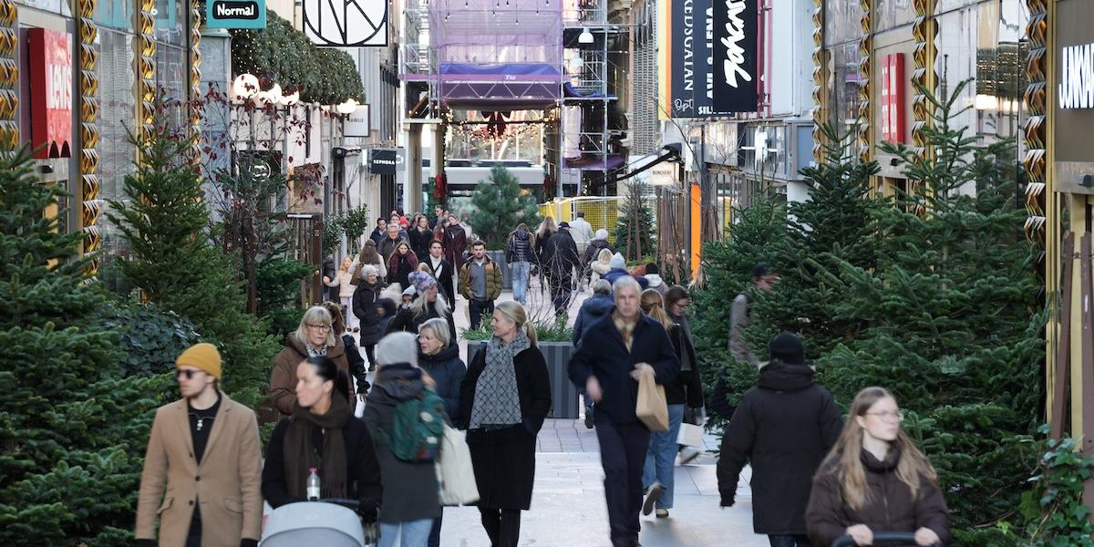 Människor promenerar på julpyntad shoppinggata i november.