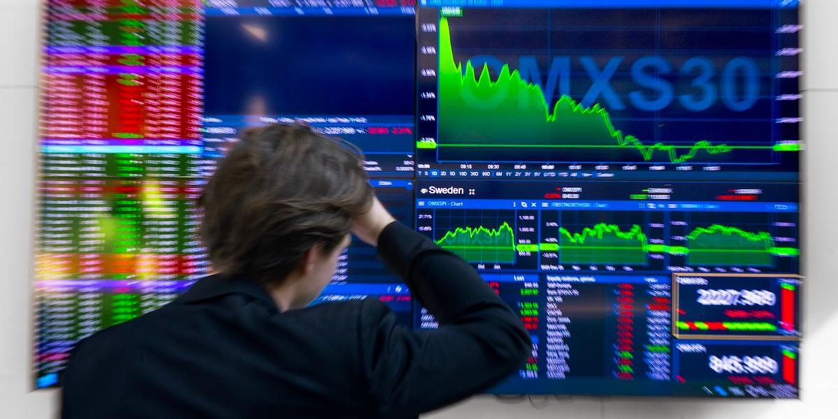 Man framför skärm med fallande aktiekurser på Stockholmsbörsen.